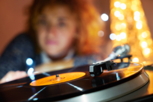 Woman sets up a record player amidst Christmas decorations.