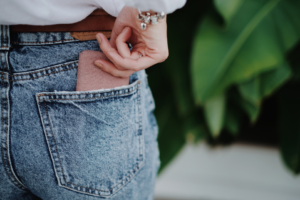 Woman slides her smart phone into the back pocket of her jeans.