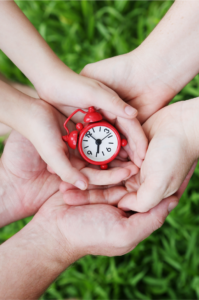 Hands of family members holding a tiny, red alarm clock