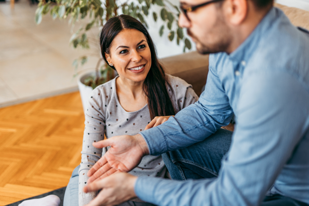 Smiling woman attentively listening to a man during a casual conversation at home about hearing God's voice.